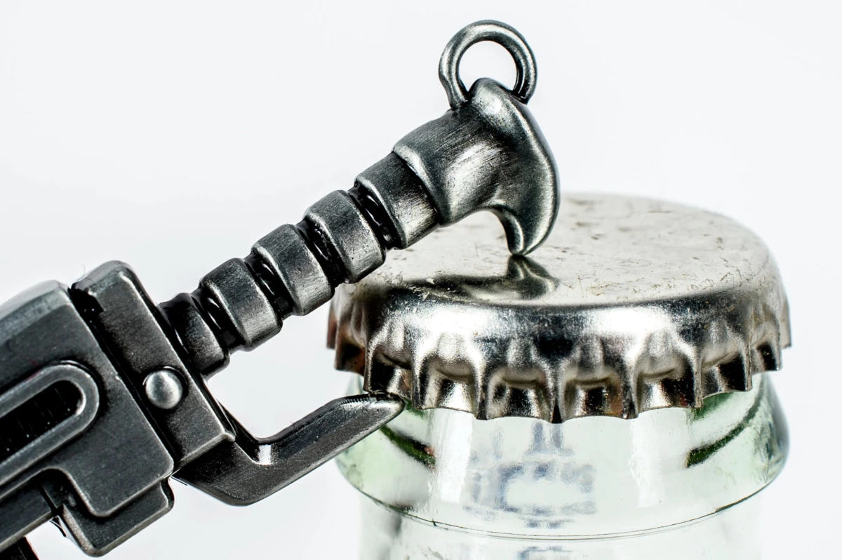 Chainsword bottle opener hooked under a bottle cap, close-up