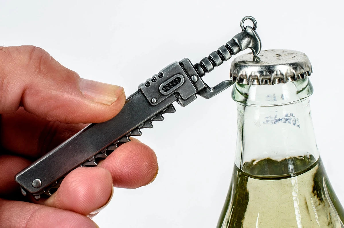Hand using the Warhammer 40,000 chainsword bottle opener to open a glass bottle