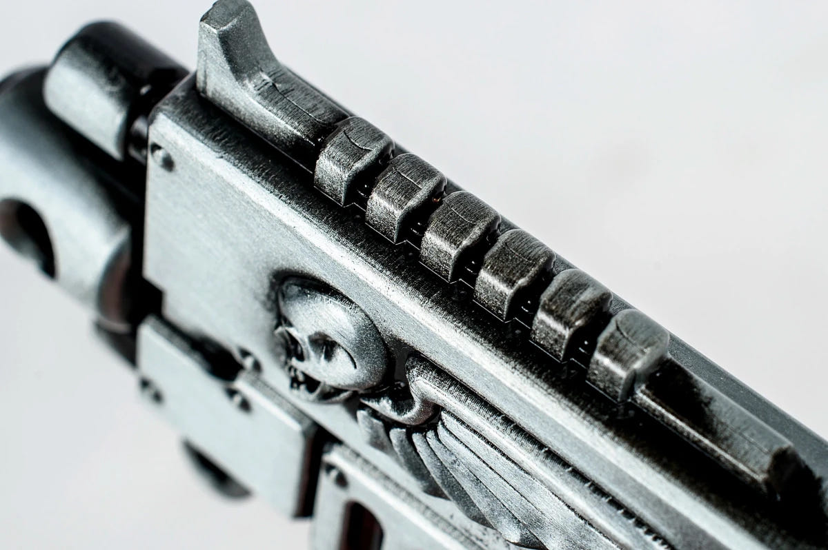 Close-up of the Bolt Rifle bottle opener's winged skull and barrel detail