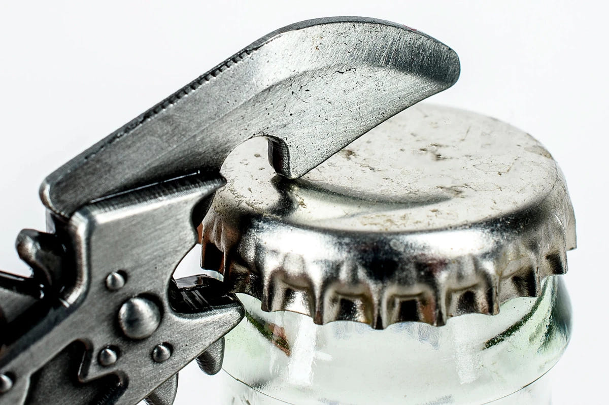 Chaos chainsword bottle opener lifting a metal bottle cap, close-up