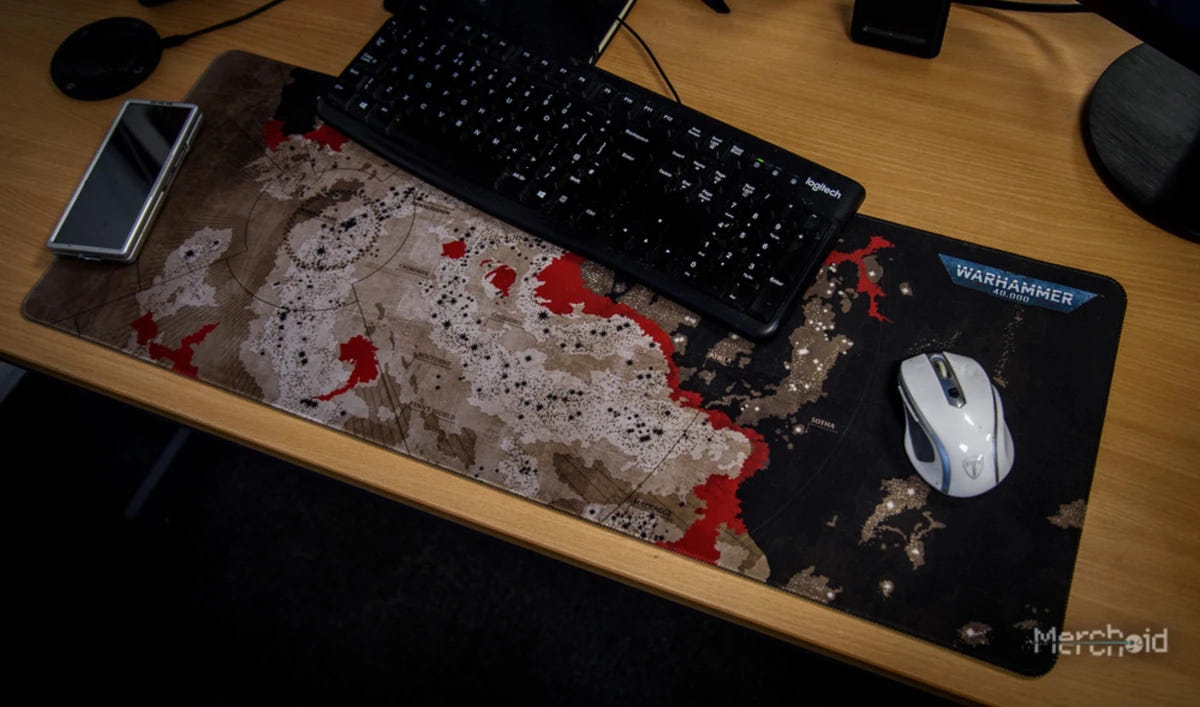 Warhammer 40,000 Galaxy map desk mat on a desk under a keyboard and mouse