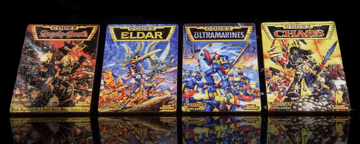 Warhammer 40,000 Second Edition codex coasters lined up side by side on a reflective black surface
