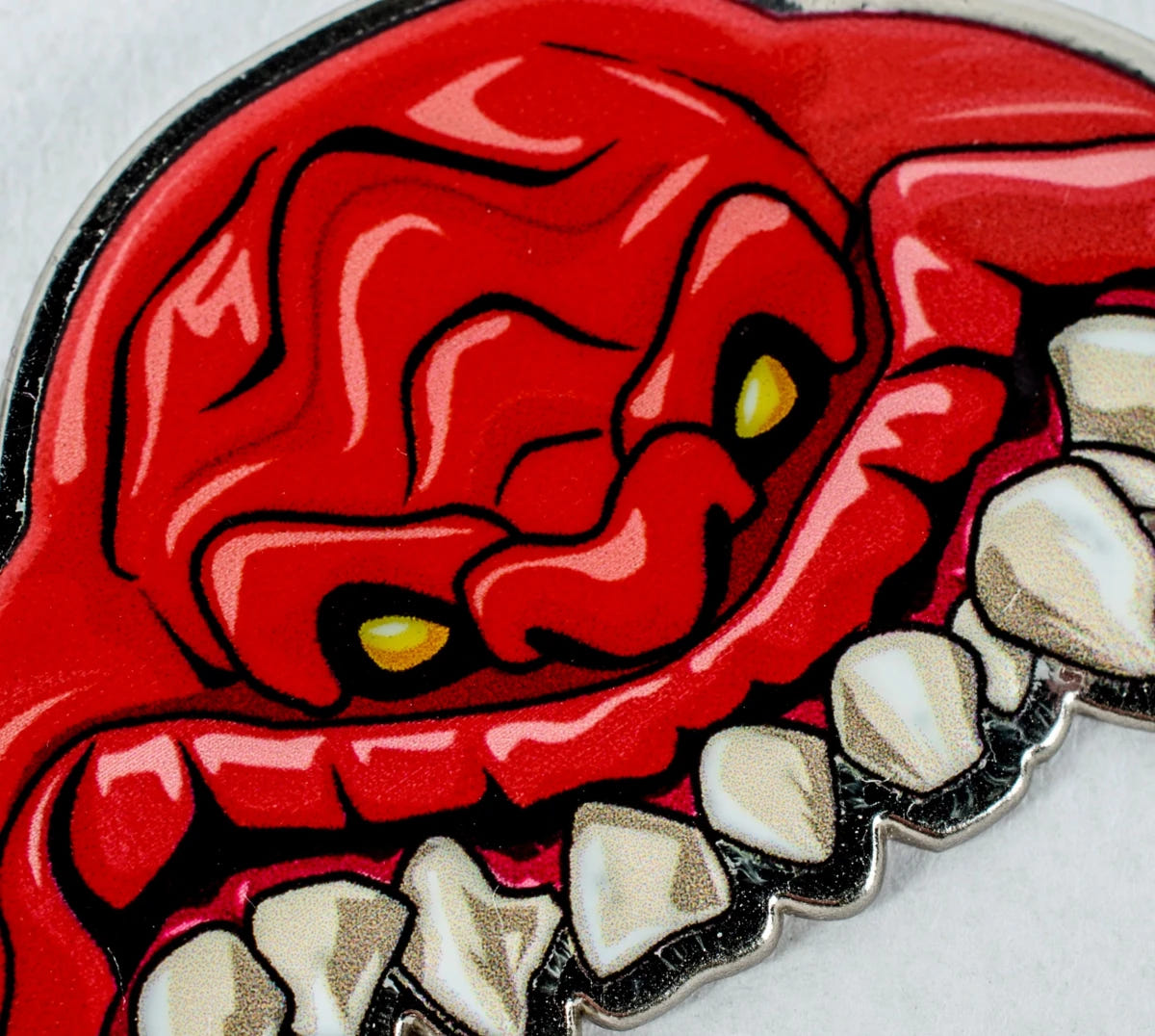 Close-up of the red enamel Squig face and yellow eyes on the bottle opener