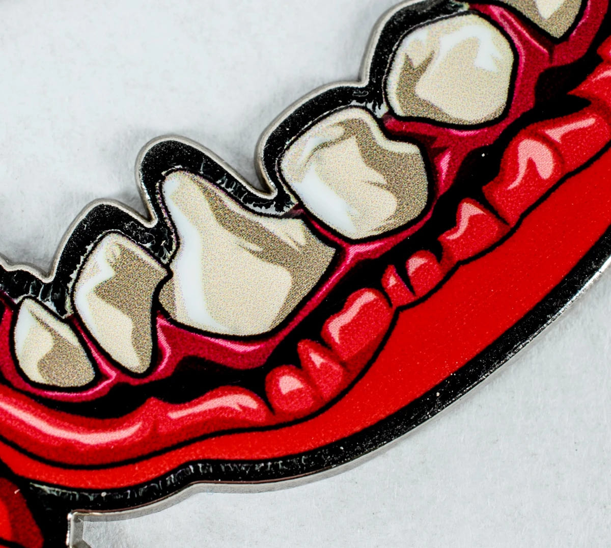 Close-up of the enamel teeth and black outline on the Squig bottle opener