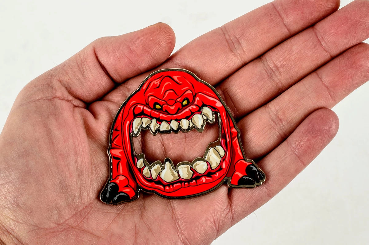 Red Warhammer 40,000 Squig bottle opener held in an open hand to show its size
