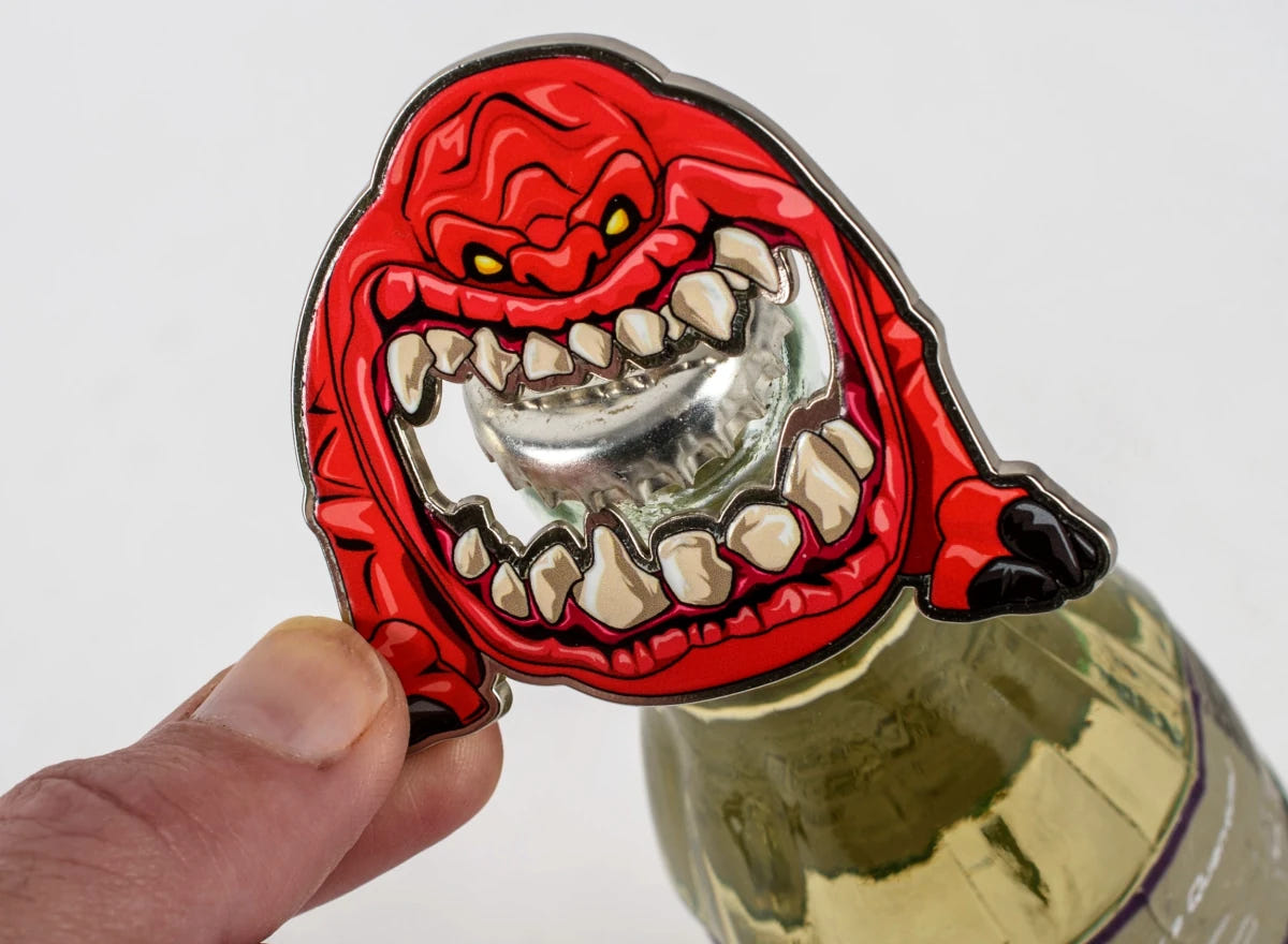 Warhammer 40,000 Squig bottle opener prising the cap off a glass bottle