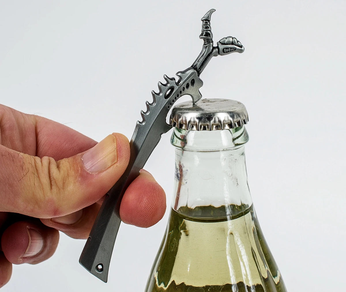 Hand using the Tyranid Bonesword bottle opener on a glass bottle, side view