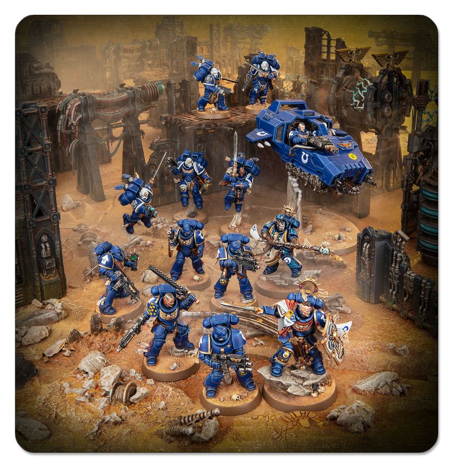 A tabletop gaming miniature army scene featuring blue armored space marine figures and a blue vehicle on a dusty, ruined sci-fi battlefield diorama. The figures are mounted on round bases, with the scene rendered in a warm brown and gold environment.