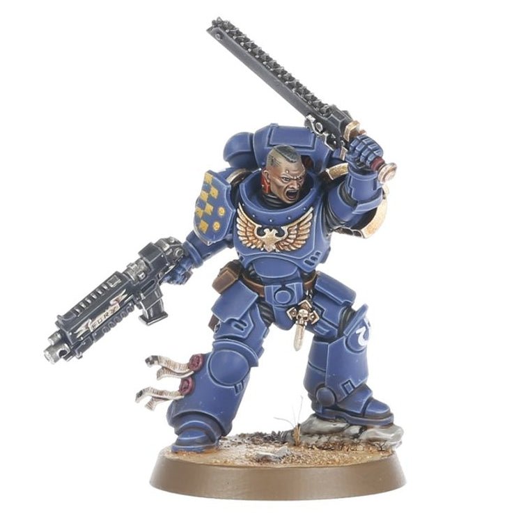 A painted miniature figurine of a blue armored space marine warrior holding a chainsword and a rifle, standing on a round base against a plain white background.