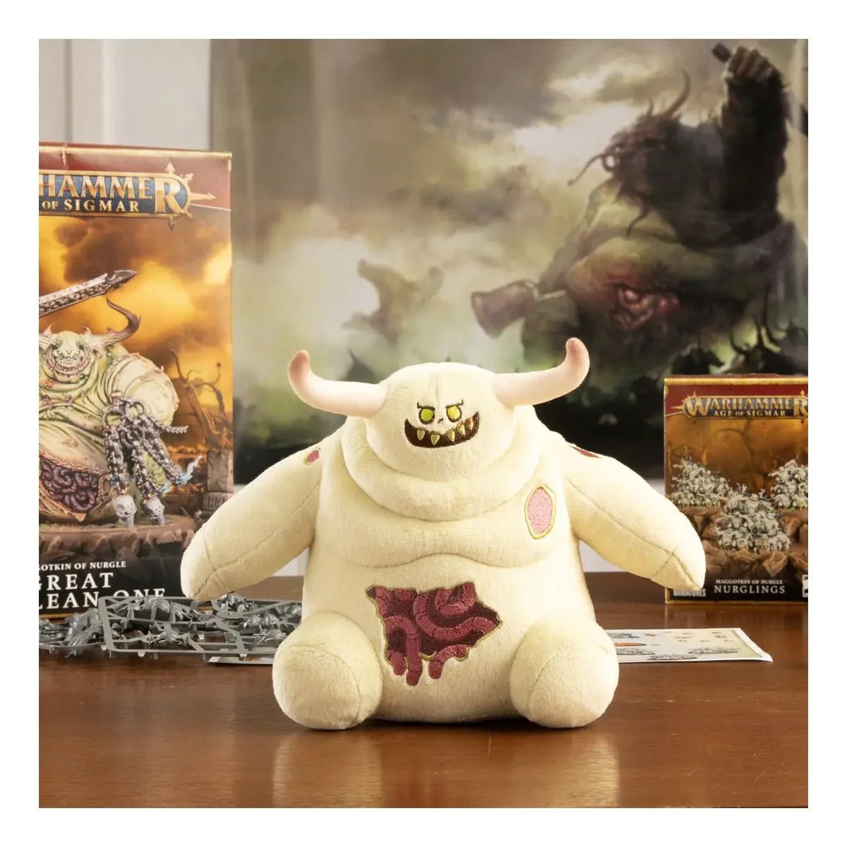 Little Unclean One plush by TOMY on a table in front of Warhammer boxes and Nurgle artwork