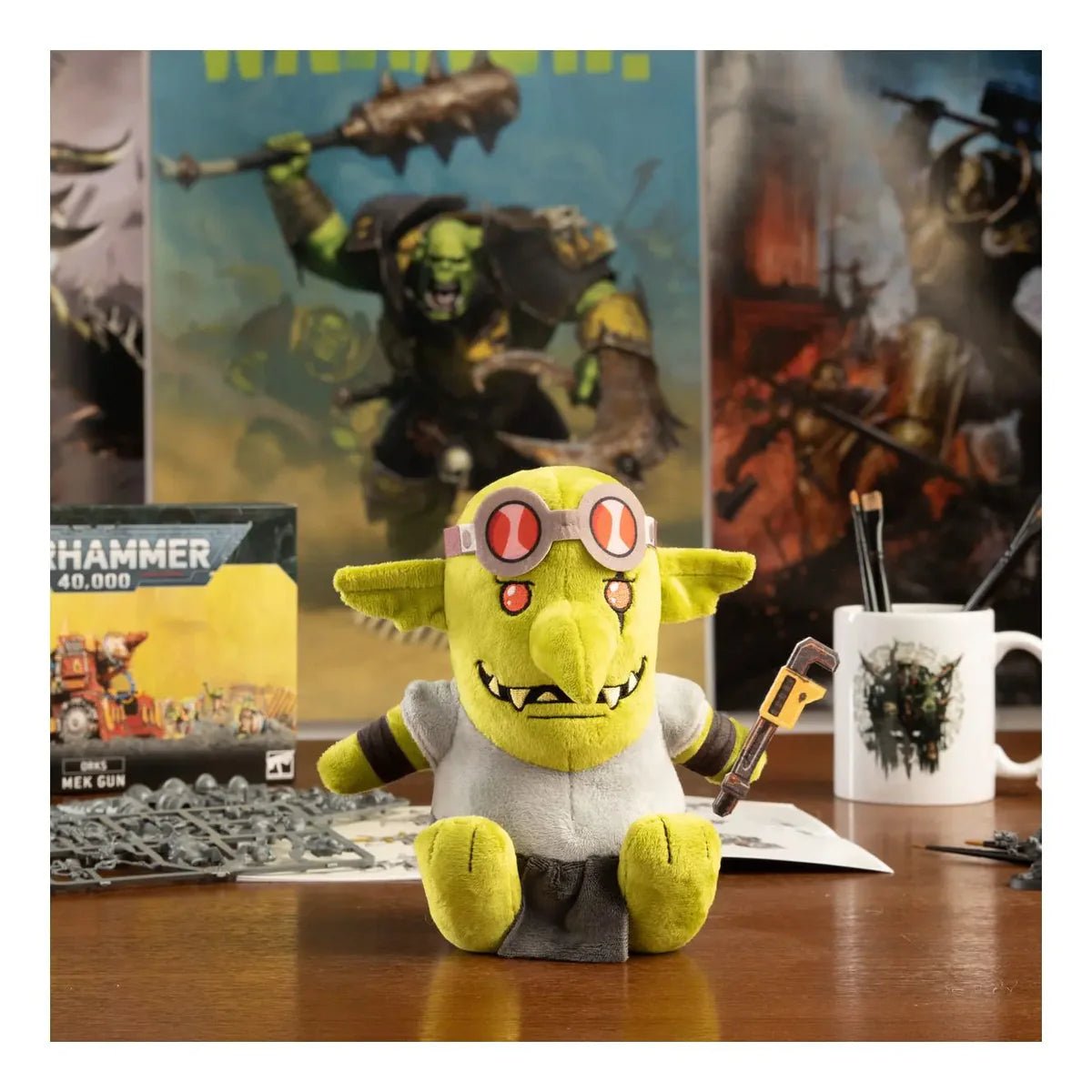 TOMY Warhammer Spanna Grot plush on a hobby desk beside Ork miniatures and a mug