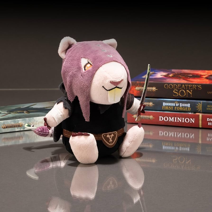 TOMY Skaven Deathmaster plush sitting on a shelf beside a stack of Warhammer novels