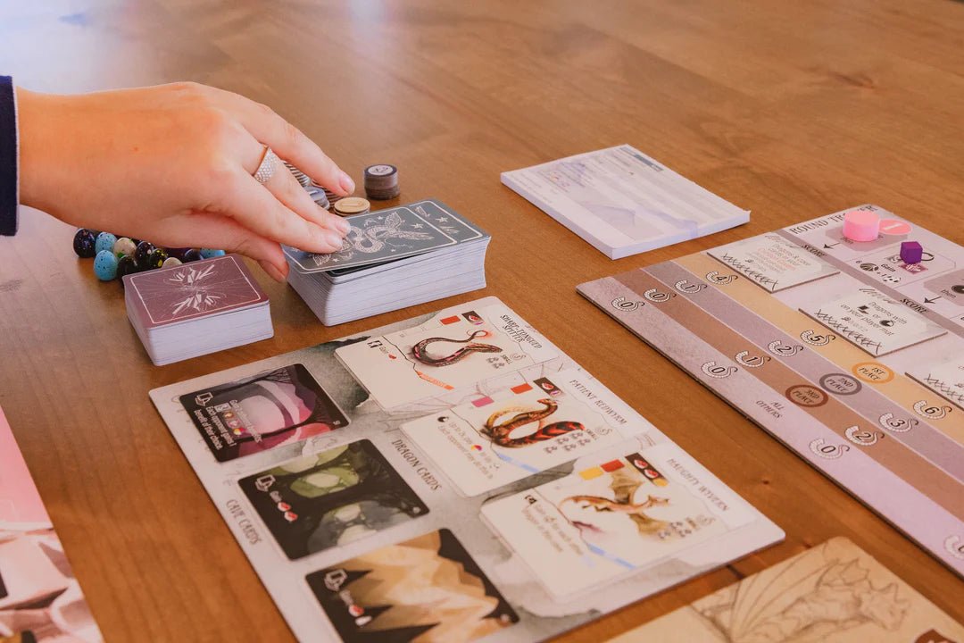 Player drawing Wyrmspan cave cards beside a player mat of dragon cards