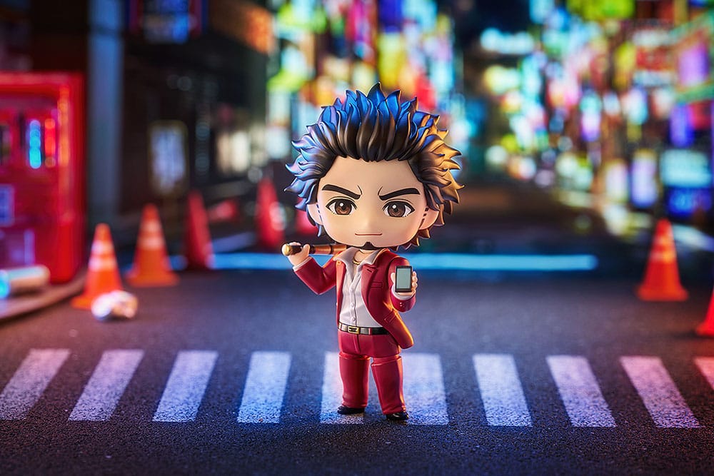 Ichiban Kasuga Nendoroid holding his phone on a night-time zebra crossing with traffic cones